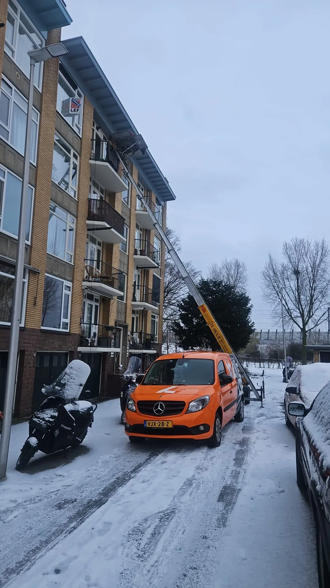 Verhuislift ingezet bij flatgebouw in de sneeuw, winterdag